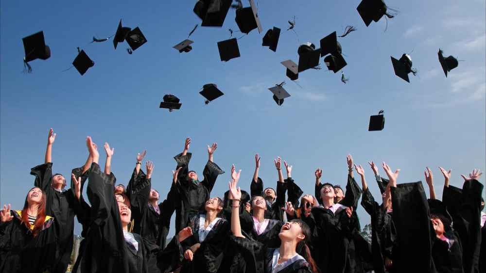 Newly Graduated People Wearing Black Academy Gowns Throwing Hats Up in the Air